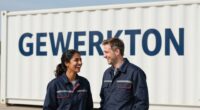 Two professionals in dark blue workwear laughing in front of a white site container with the GEWERKTON lettering
